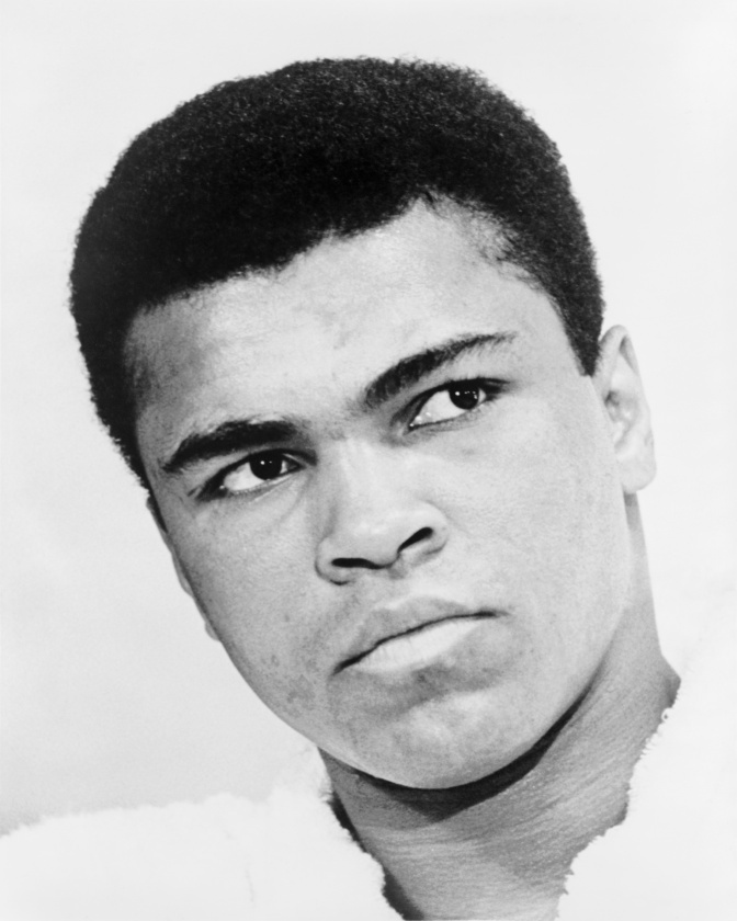 Schwarz-weiß-Foto von Muhammad Ali. Er hat krauses Haar und dunkle Haut und schaut seitlich an der Kamera vorbei.