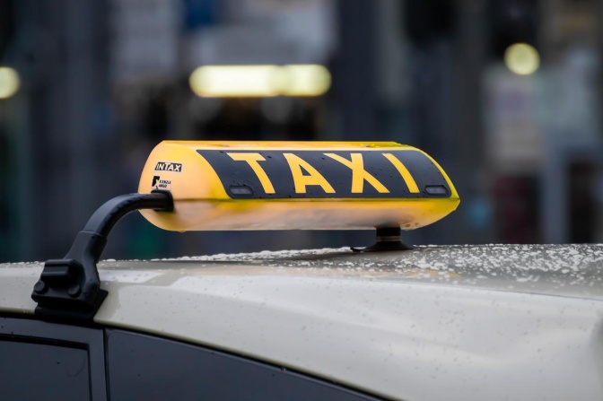Das gelb-schwarze Taxischild auf dem Dach eines Autos