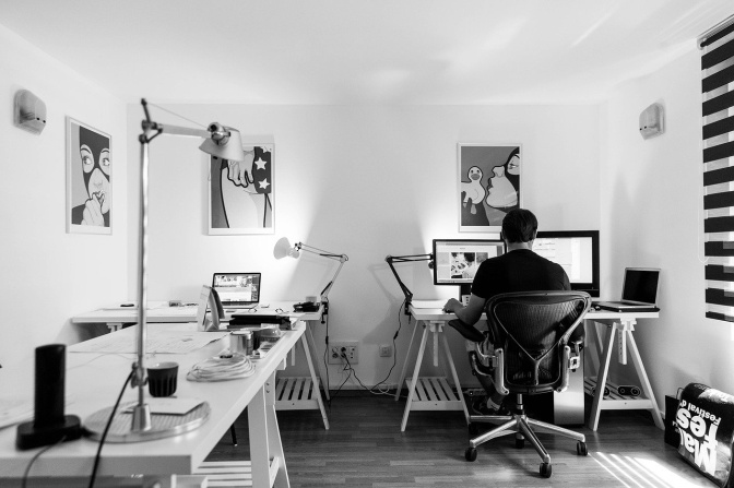 Schwarz-weiß Foto eines Mannes, der im Büro am Rechner arbeitet