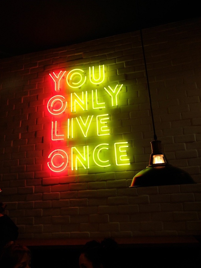 Neonbuchstaben an der Wand bilden die Worte: You only live once.