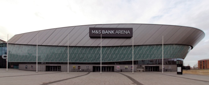 Ein langgezogenes, asymmetrisches Gebäude mit großen Fenstern. Über dem Eingang ein großes Schild mit dem Schriftzug M&S Bank Arena