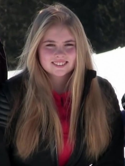 Eine junge Frau mit langen, glatten blonden Haaren. Sie lächelt in die Kamera und trägt einen roten Pullover und eine schwarze Lederjacke.