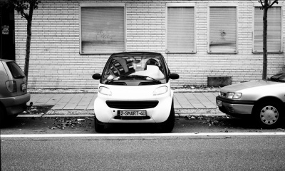 Ein Smart, zwischen 2 anderen Autos quer zur Straße eingeparkt.