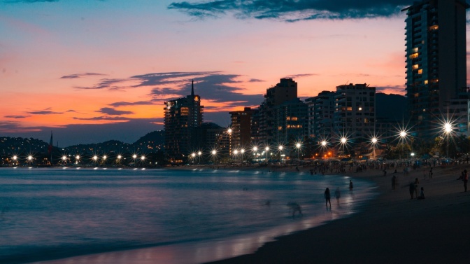 Der Strand der mexikanischen Stadt Acapulco bei Sonnenuntergang, im Hintergrund die Skyline.