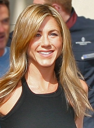 Jennifer Aniston mit glatten blonden Haaren und einem schwarzen, schlichten Kleid