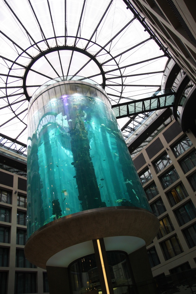 Ein zylinderförmiges Aquarium unter dem Glasdach eines Hotels