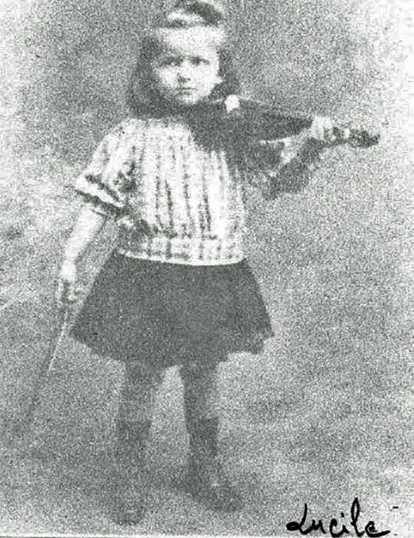 Ein altes schwarz-weiß-Foto eines kleinen Mädchens mit einer Geige. Sie hat sorgfältig frisiertes kinnlanges Haare und trägt Rock und Bluse.