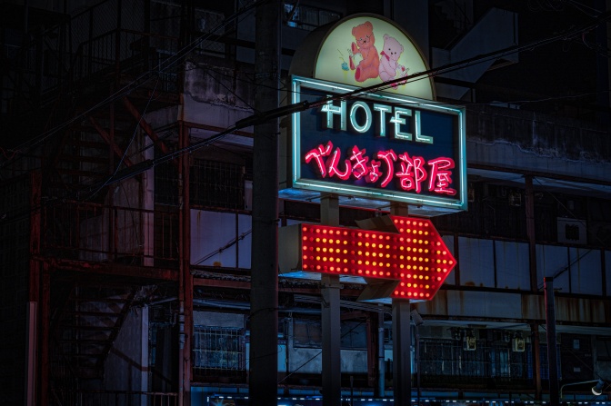Eine Neonreklame zeigt den Eingang eines Hotels auf Englisch und Chinesisch.