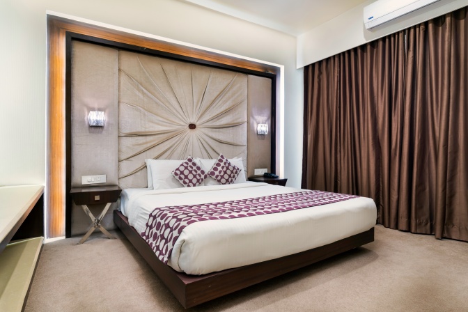 Ein Doppelbett in einem Hotelzimmer mit dunklen, zugezogenen Gardinen