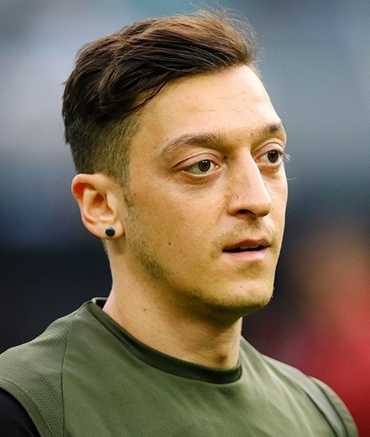Mesut Özil mit olivfarbener Haut und dunkelbraunen Haaren. Er trägt ein grünes T-Shirt.