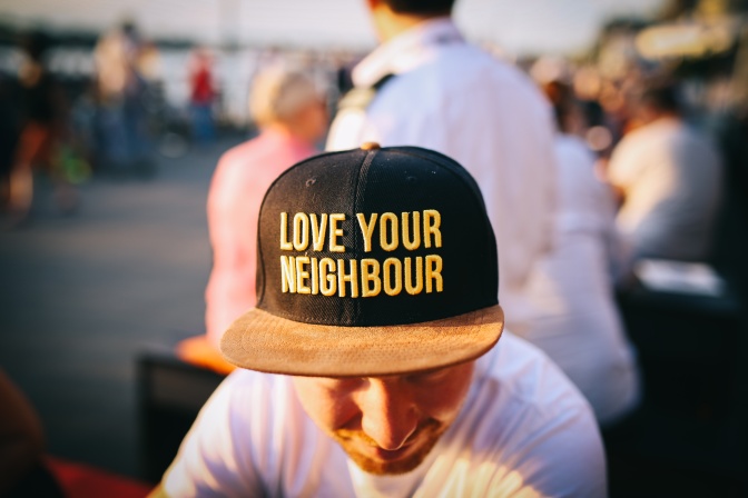 Ein Mann mit einer Schirmmütze mit der Aufschrift Love your neighbour, also auf Deutsch: Liebe deinen Nachbarn