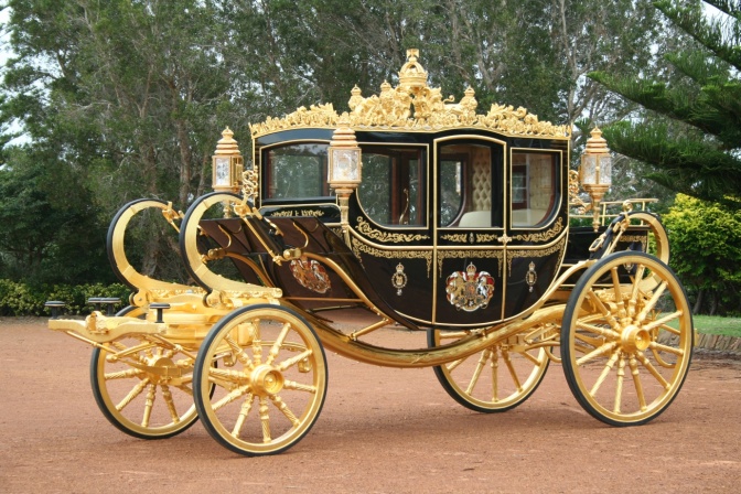 Eine schwarze Kutsche mit goldenen Rädern und viel goldenem Schmuck. Die hat eine ovale Form.