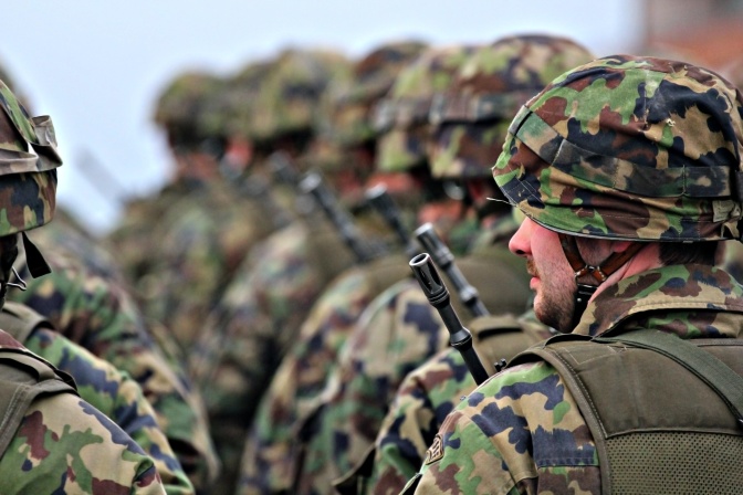 Soldaten in Flechtern mit schusssicherer Weste und Helm stehen in exakten Reihen vor- und nebeneinander.