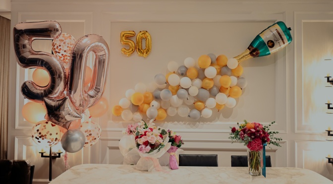Ein für eine Party geschmückter Raum mit vielen Luftballons, unter anderem einer großen, goldenen 50.