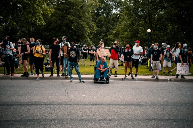 Eine Gruppe von Demonstrant*innen steht am Straßenrand. Einzelne Demonstrant*innen haben sichtbare Behinderungen.