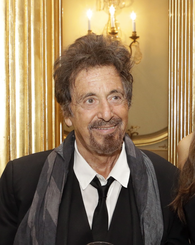 Al Pacino in einem Anzug mit Krawatte und einem grauen Schal. Er hat einen Vollbart und wuschelige dunkle Haare.
