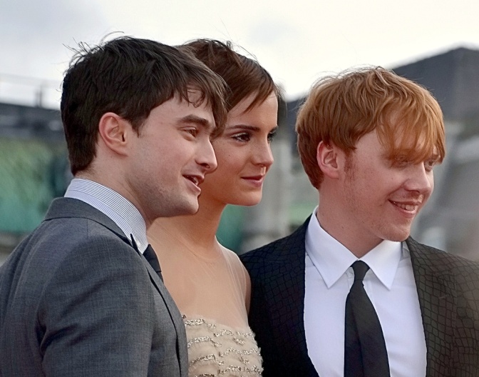 Die 3 Schauspieler*innen stehen in festlicher Kleidung nebeneinander und lächeln in die Kamera.