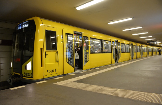 Eine gelbe U-Bahn steht mit geöffneten Türen an einem leeren Gleis.