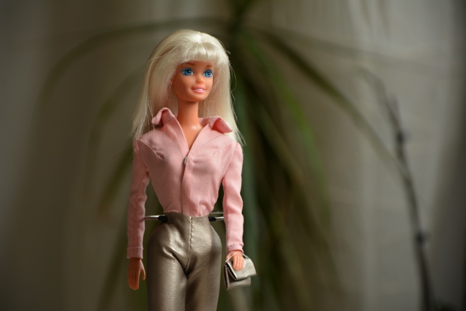 Eine blonde Barbie in hellrosa Bluse.