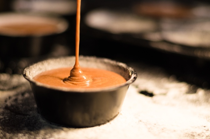 Flüssige Schokolade wird in eine Pralinenform aus Schokolade gegossen.