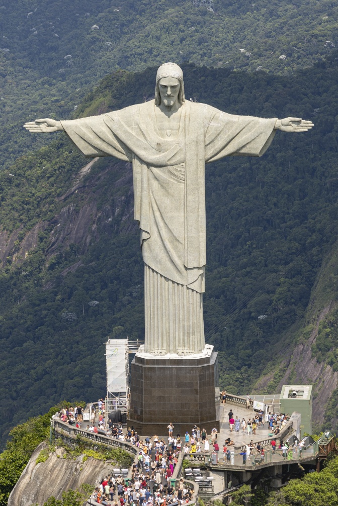 Eine übergroße Jesusfigur aus hellem Stein mit ausgebreiteten Armen.