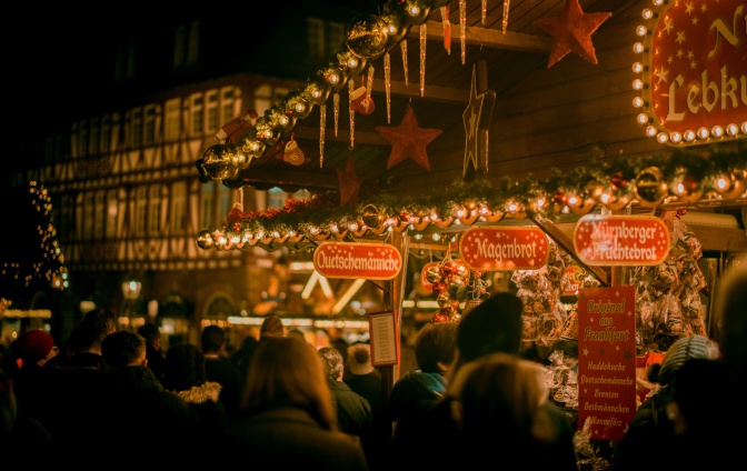 Ein Stand mit Lebkuchen und Süßigkeiten auf einem Weihnachtsmarkt, davor viele Menschen.