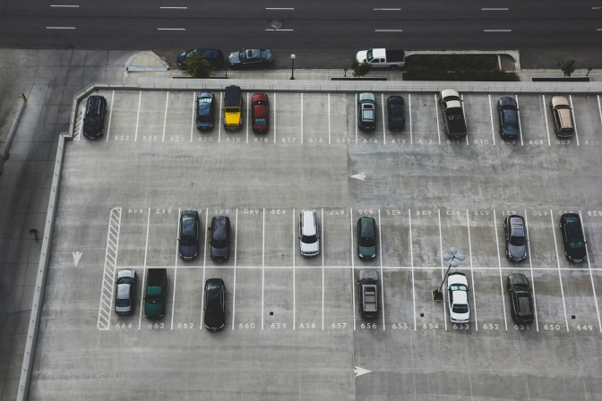 Mehrere Autos parken auf einem großen Parkplatz, viele Parkplätze sind noch frei.