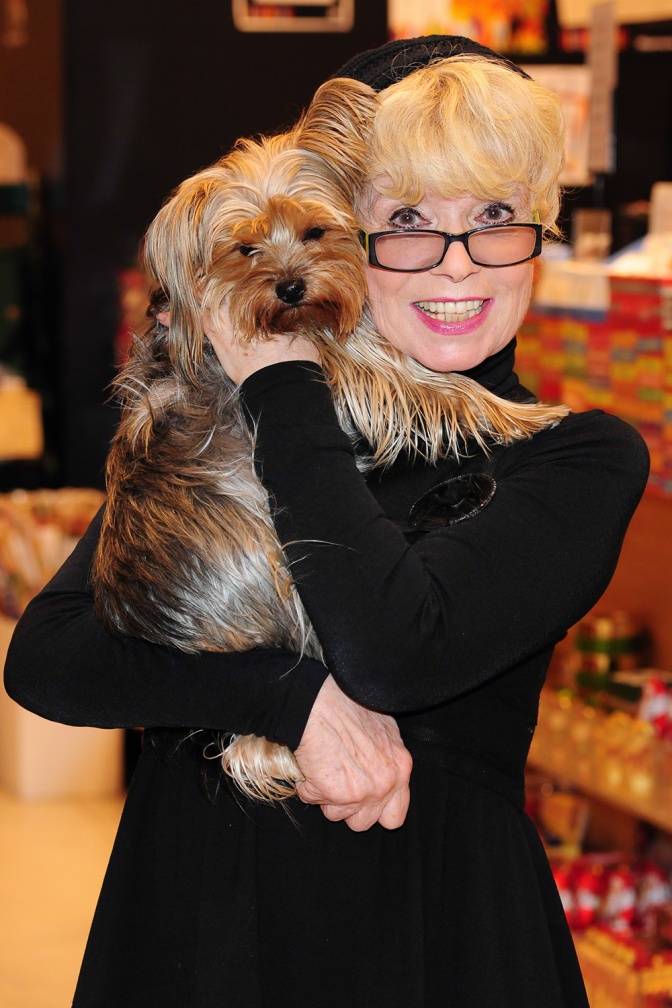 Ingrid Steeger mit einem kleinen Hund im Arm. Sie hat kurze blonde Haare und trägt eine runde, schwarze Brille.