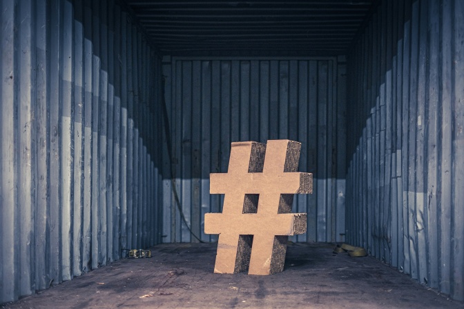Ein Hashtag aus Pappe steht mittig in einem leeren Raum.
