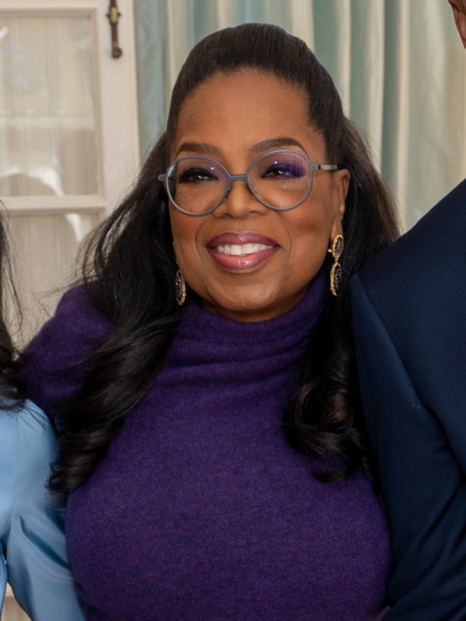 Oprah Winfrey mit brille in einem lilafarbenen Rollkragenpullover.