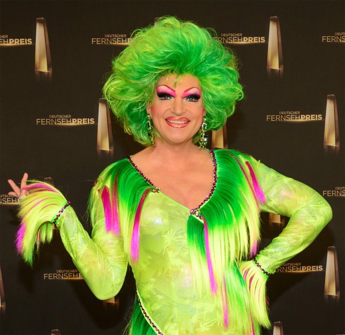 Olivia Jones mit grüner Perücke und in neongrünem Overall.