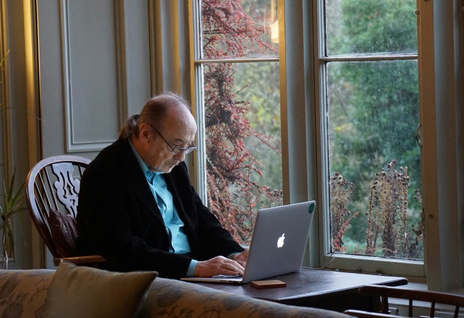 Ein älterer Mann mit Halbglatze arbeitet an einem Laptop.