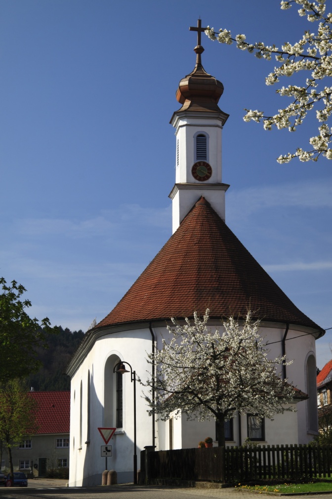 Eine weiß verputzte Kirche mit einem runden Kirchenschiff und einem Kirchturm mit zwiebelförmigem Dach.