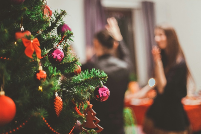 Ein geschmückter Weihnachtsbaum, im Hintergrund unscharf mehrere Menschen