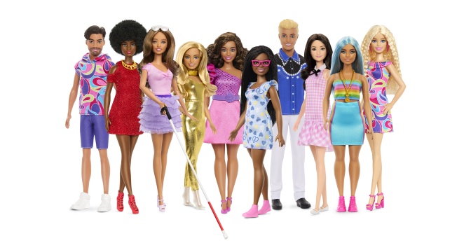 Verschiedene Barbies und Kens mit verschiedenen Hautfarben und verschiedenen optischen Merkmalen. Im Vordergrund eine Barbie mit einem Langstock.