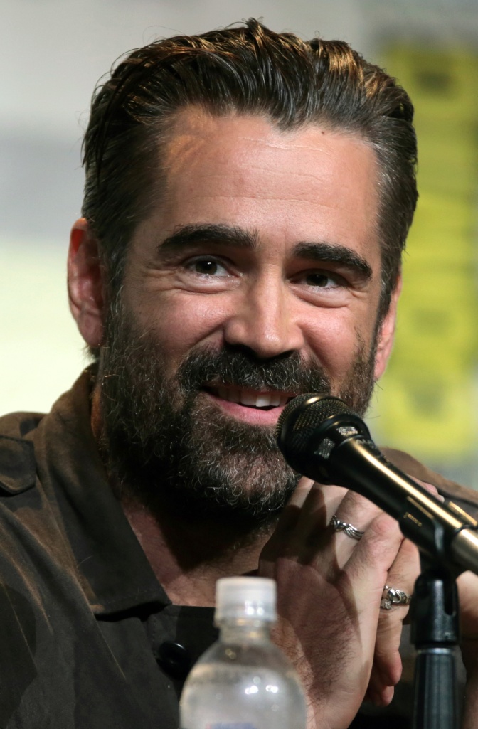 Colin Farrell mit braunen Haaren und Vollbart. Er spricht lächelnd in ein Mikrofon.