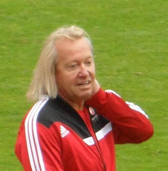 Robert Geiss mit kinnlangen blonden Haaren in einer Trainingsjacke auf dem Fußballfeld