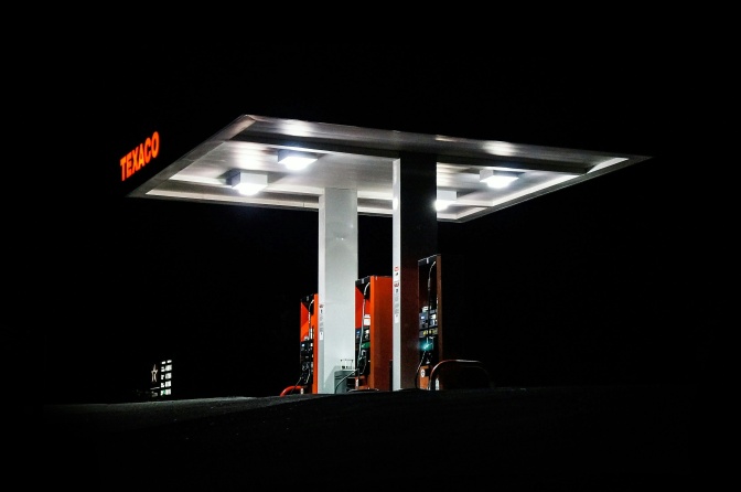 Eine beleuchtete Tankstelle im Dunkeln. Der Firmenname TEXACO leuchtet in rot.