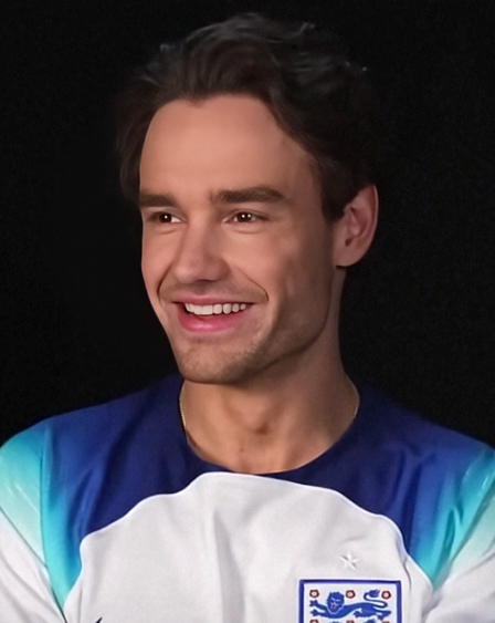 Liam Payne lächelnd mit kurzen braunen Haaren in einem blau-weißen Shirt.