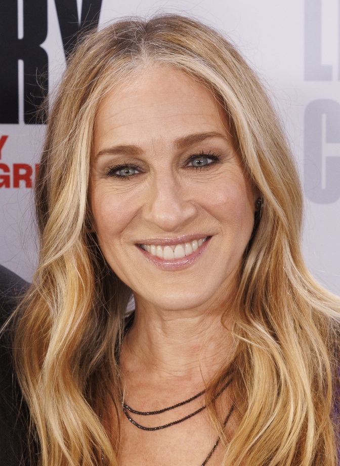 Sarah Jessica Parker mit langen, glatten blonden Haaren. Sie schaut lächelnd in die Kamera.