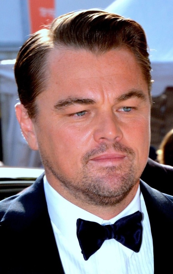 Leonardo DiCaprio In Anzug und Fliege mit Dreitagebart und Pomade in den Haaren.