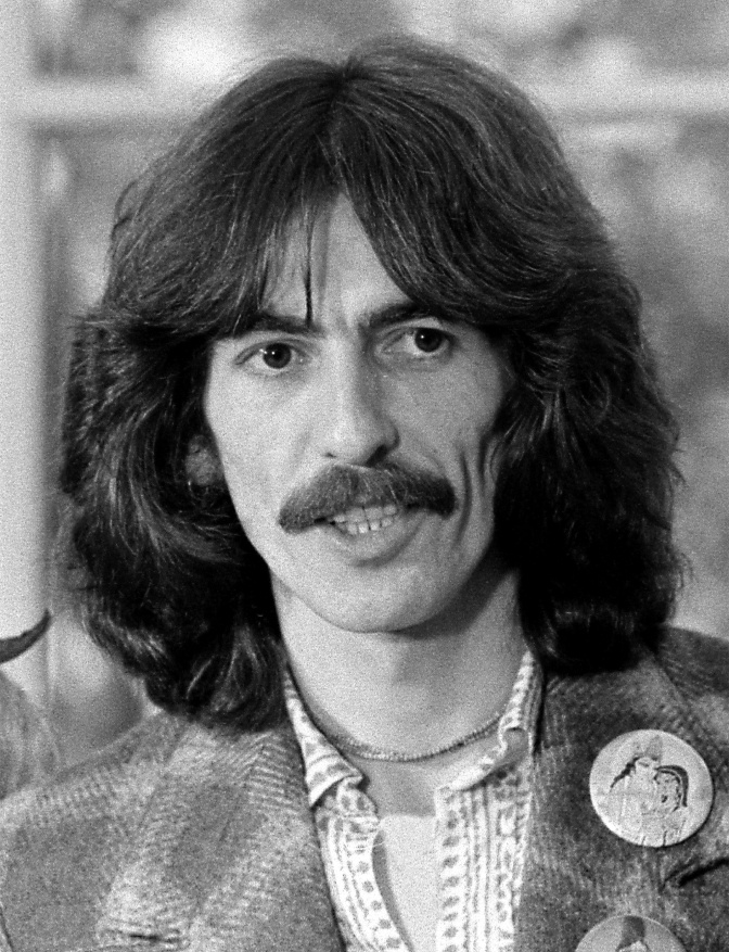 Ein schwarz-weiß-Foto des jungen George Harrison mit schulterlangen Haaren und Schnäuzer