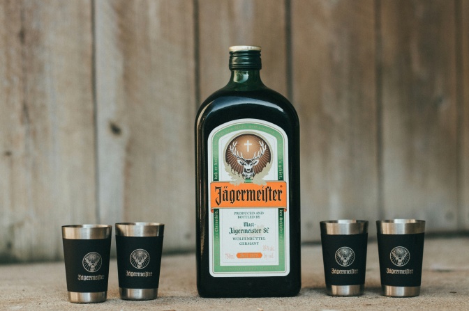 Eine Flasche Schnaps der Marke Jägermister, darum herum stehen 4 Schnapsgläser.