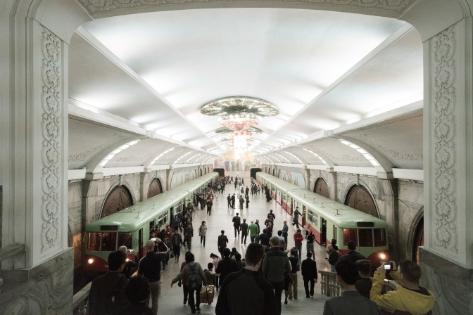 Menschen an einer Metrostation, rechts und links steht je eine U-Bahn.