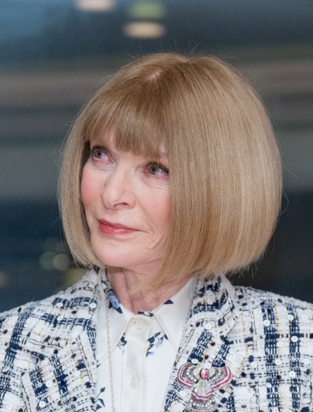 Anna Wintour in einem karierten Sakko mit einem streng geschnittenen Bob. Sie schaut seitlich an der Kamera vorbei.