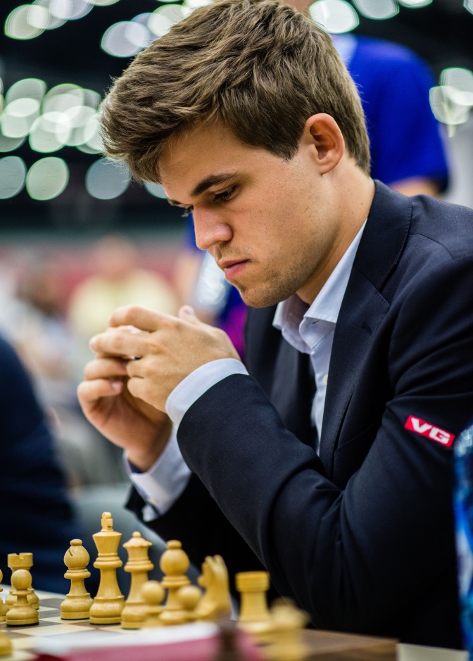 Magnus Carlsen sitzt konzentriert vor einem Schachbrett. Er spielt weiß.