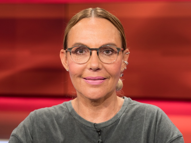 Natascha Ochsenknecht mit zurückgebundenen tot-blonden Haaren und großer runder Brille. Sie schaut direkt in die Kamera.