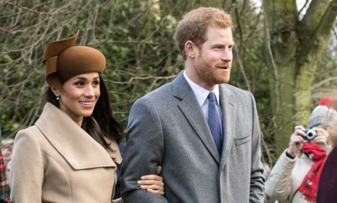 Prinz Harry und Herzogin Meghan haben sich beieinander untergehakt und tragen beide winterliche Kleidung.