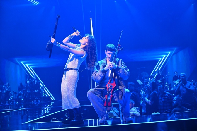 Abor und Tynna auf einer blau beleuchteten Bühne. Sie singt in ein Mikro und lehnt sich nach hinten, er spielt Cello.