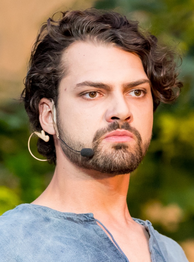 Jimi Blue Ochsenknecht mit gewellten braunen Haaren und Vollbart. Er hat ein kleines Mikro angesteckt und schaut ernst an der Kamera vorbei.